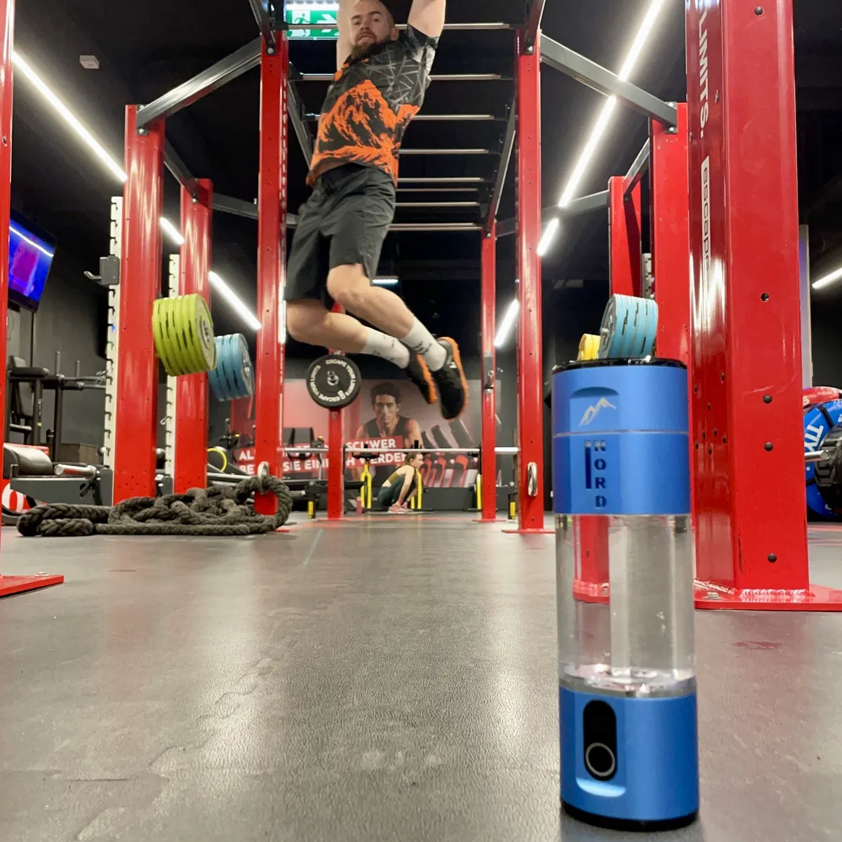 Nord Hydrogen Bottle på gulvet i træningscentret, mens Marcus Gail træner i monkey bars